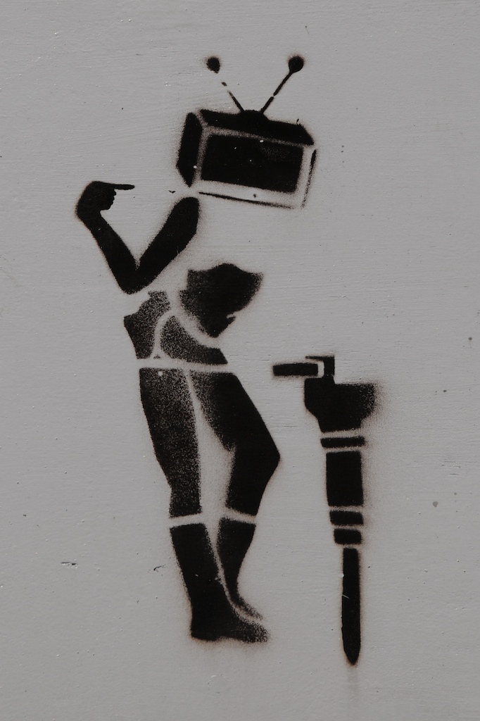 a stencil drawing of a woman with a tv on her head, an old computer tower in the background and a sink below