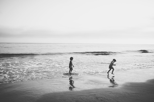 black and white po of three s running on a beach
