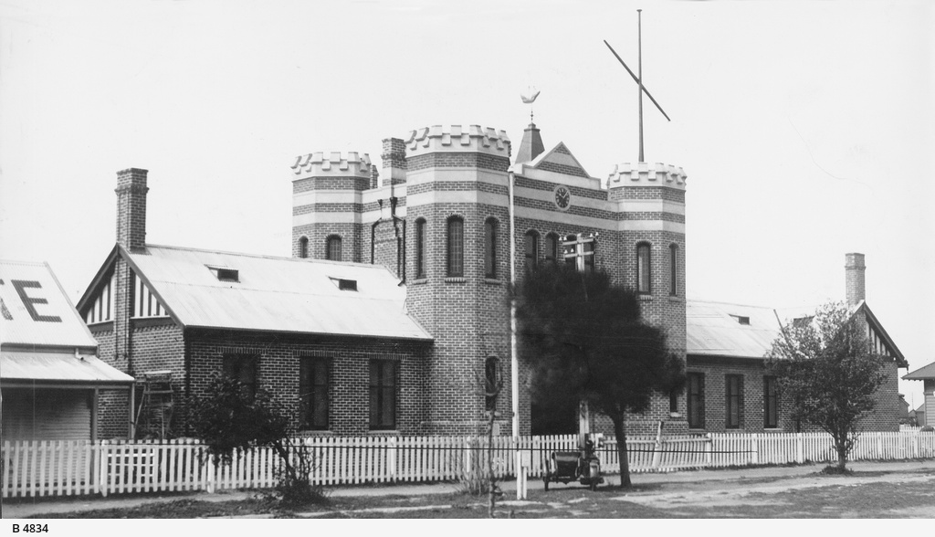 a building with two towers next to the fence