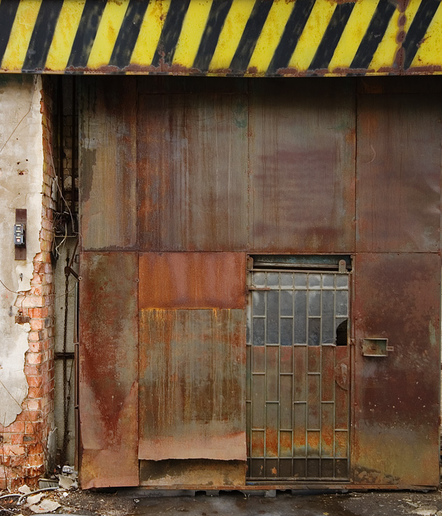 a very old metal door on an abandoned building