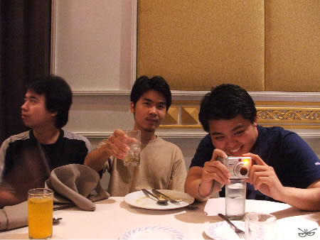 three men sitting around a table while taking pictures