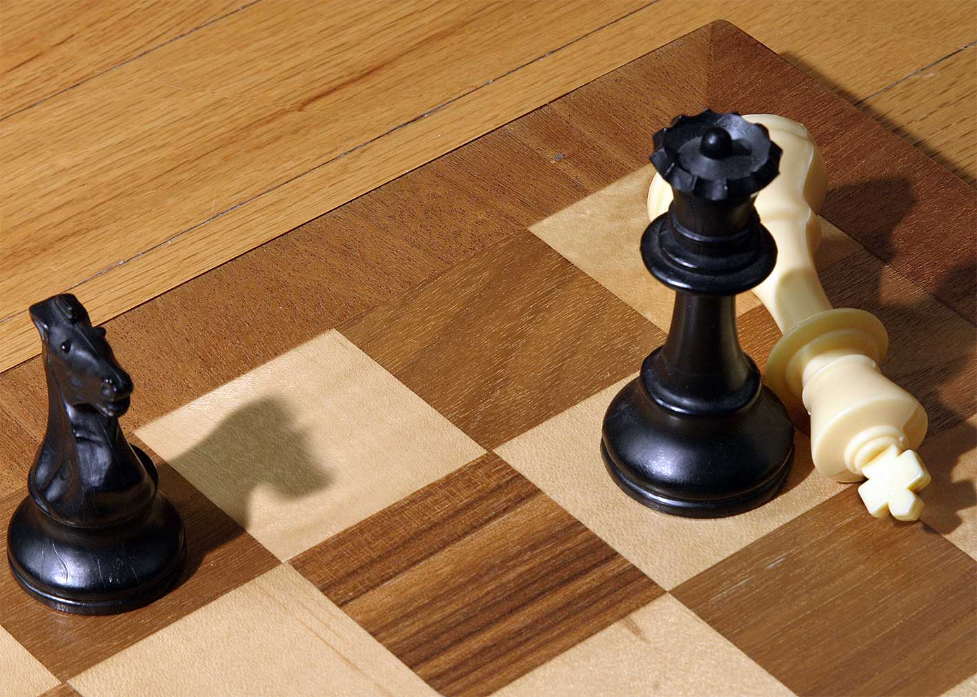 two black chess pieces stand on a checker board