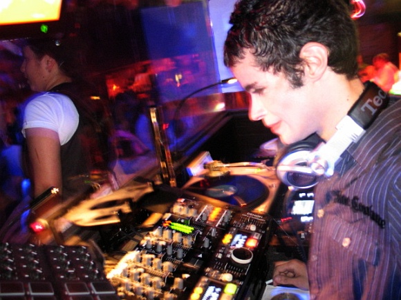 the dj in front of the monitor is holding a controller