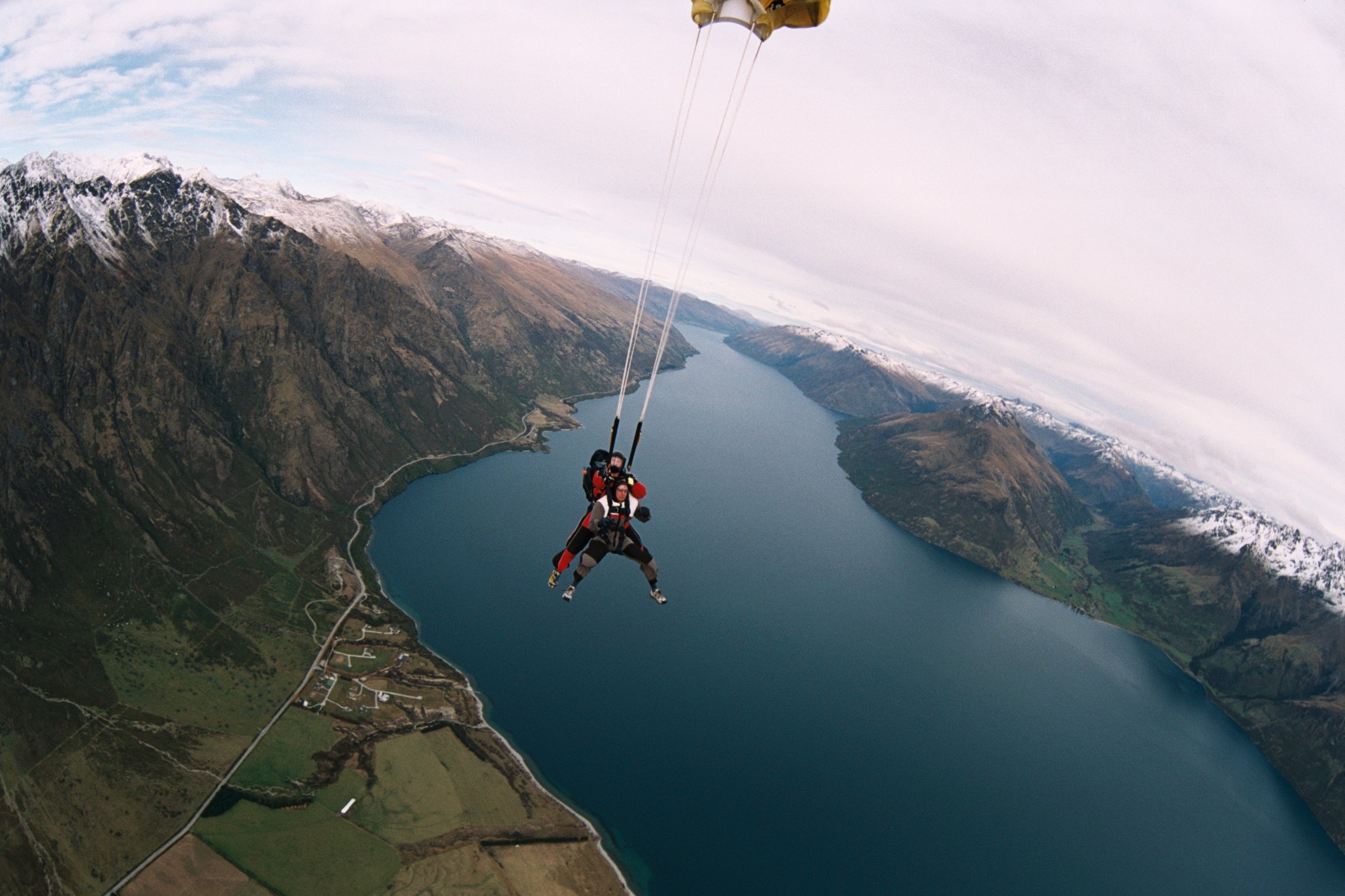 a paraglider suspended over a lake on the side of a mountain