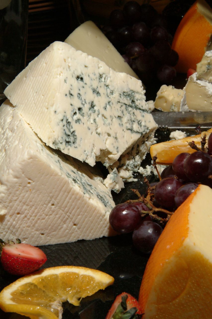 various cheeses and fruit on a black surface