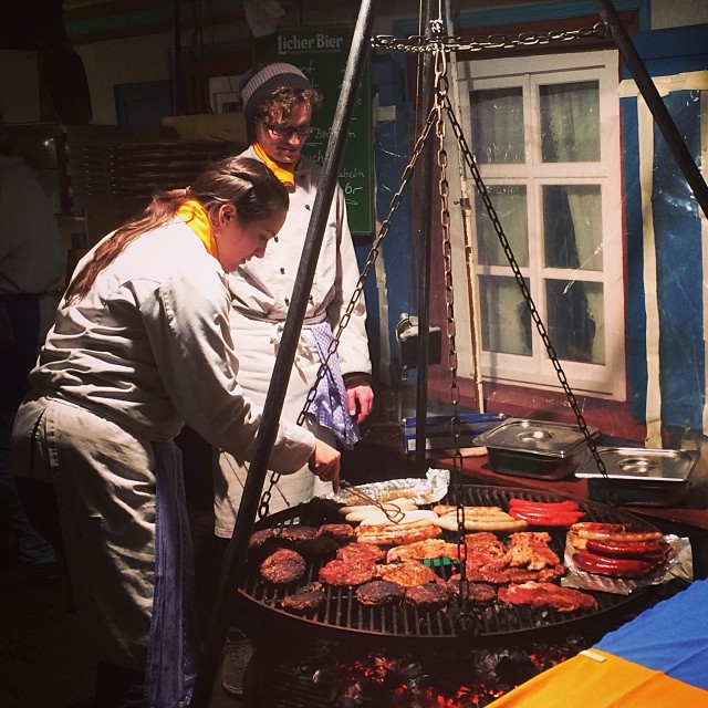 two women cook burgers on the grill in front of their building