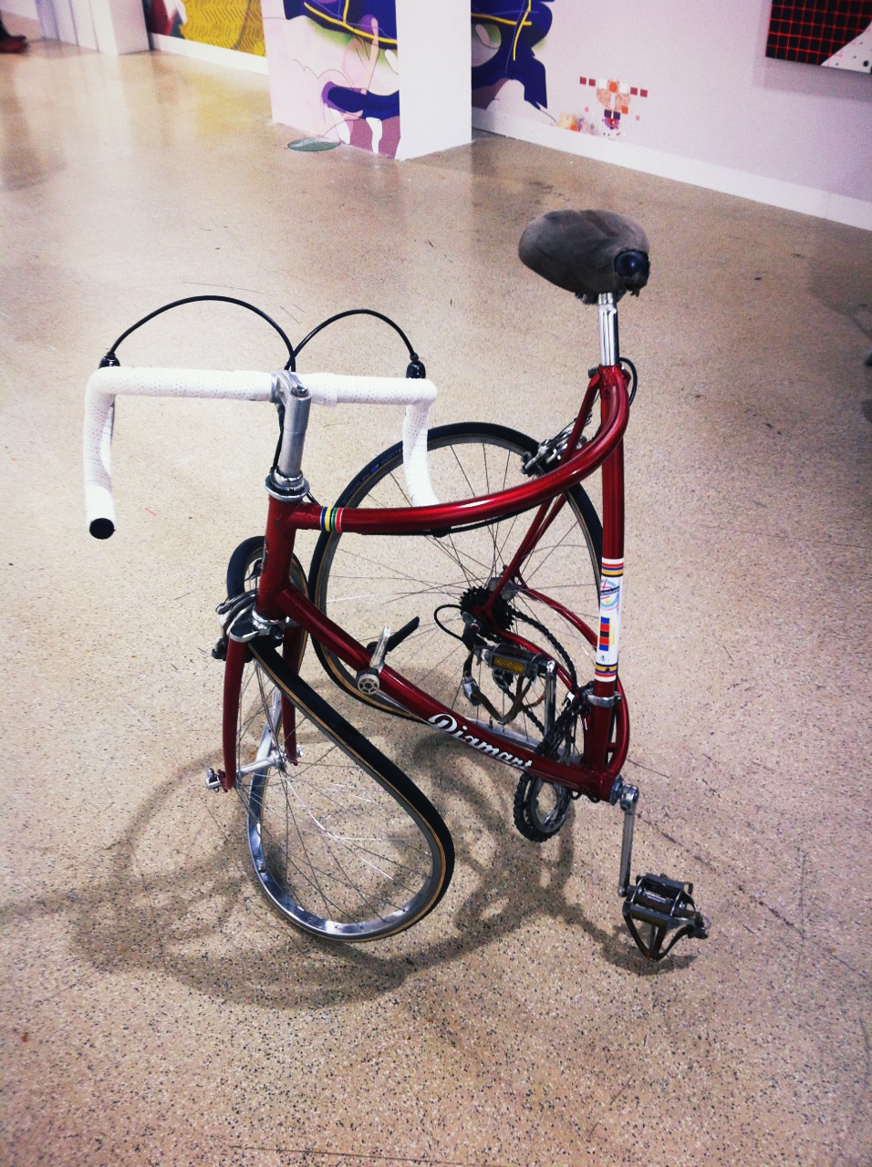 a red bike sits on the floor next to an artwork piece