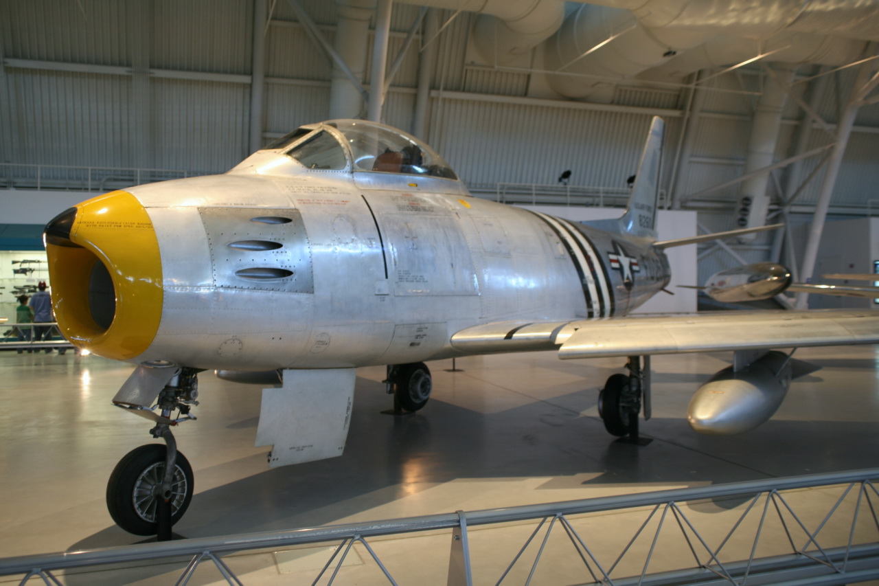 a silver airplane is displayed in a museum hangar