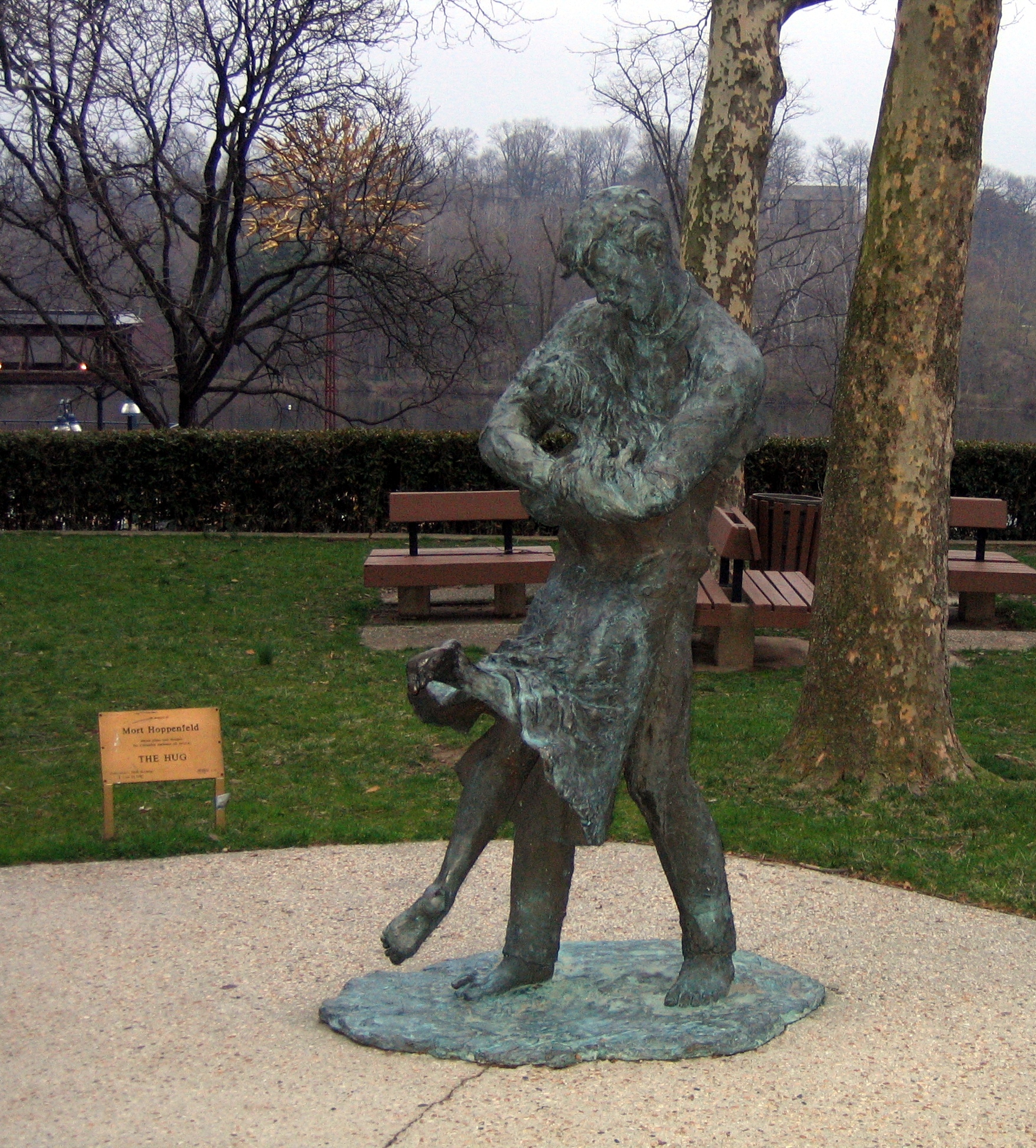 a statue in a park near benches and trees