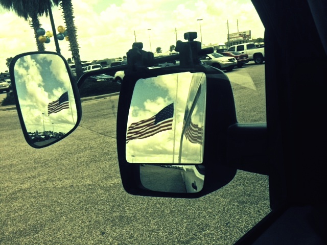 a rear view mirror shows the american flag and its reflection