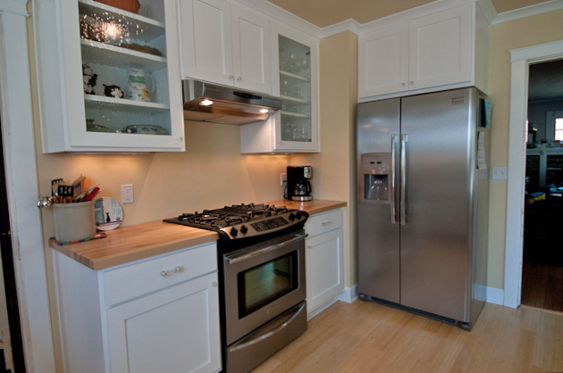 a white kitchen with an electric stove and refrigerator