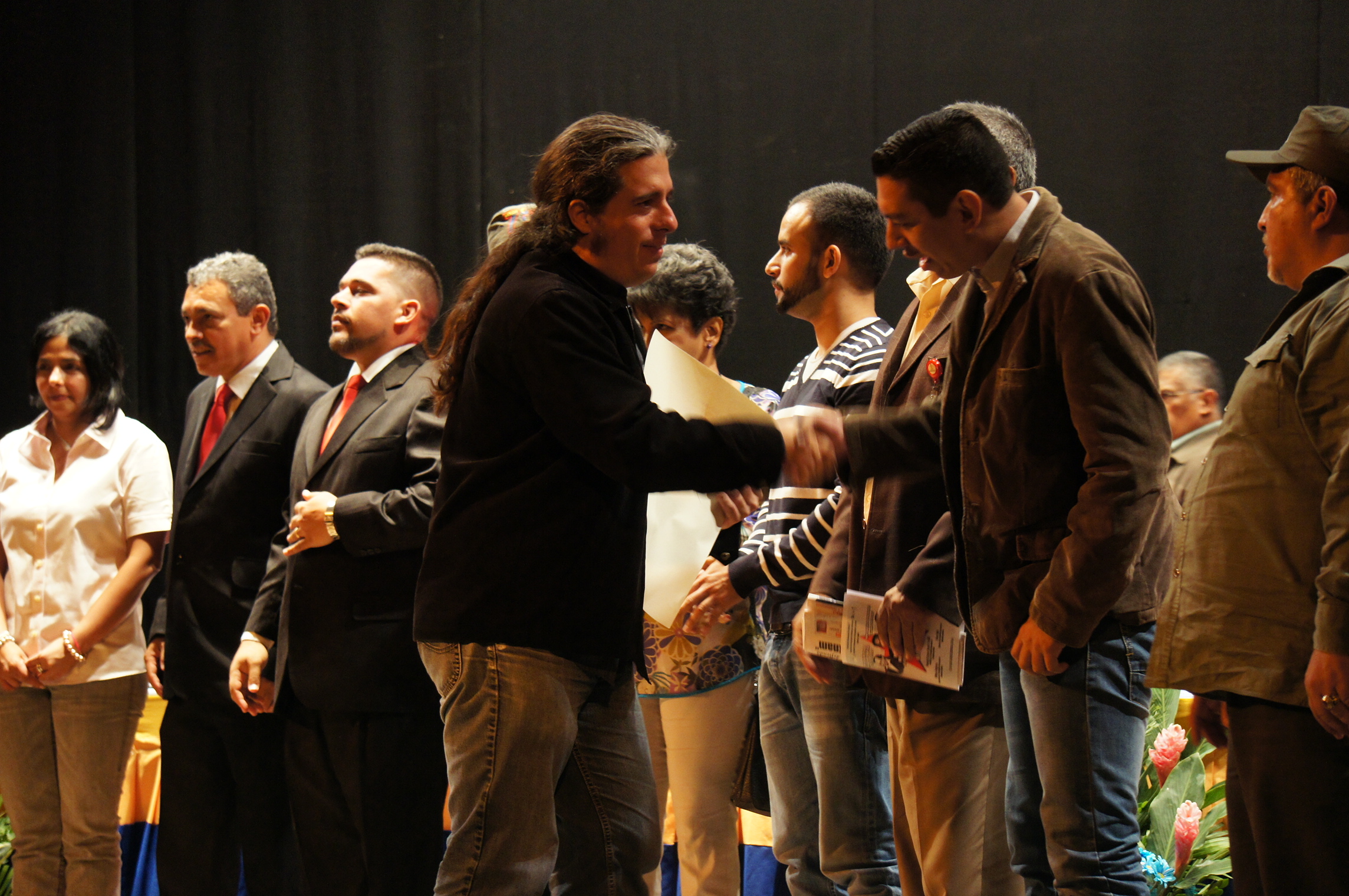 two men shaking hands at an event with others