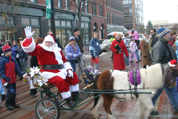 santa clause rides a horse cart down the street