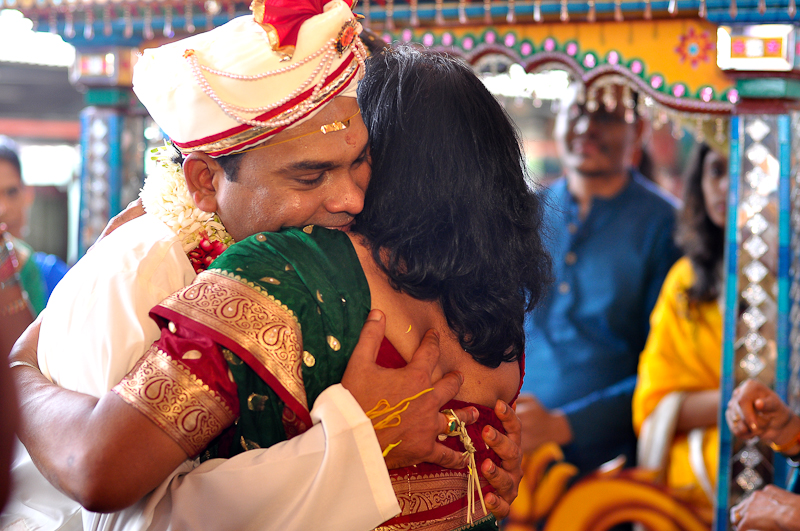 a man hugs the forehead of a woman as people look on