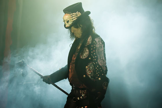 a man with an mask and top hat holding a cane