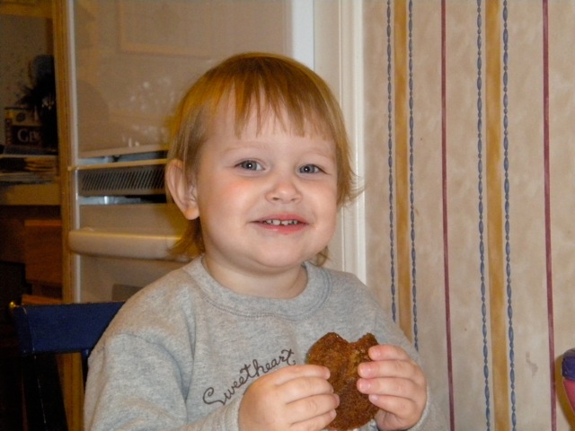 a small child sitting at the table with a piece of food