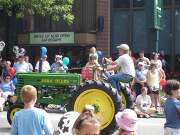 children ride on the front of a tractor while people watch