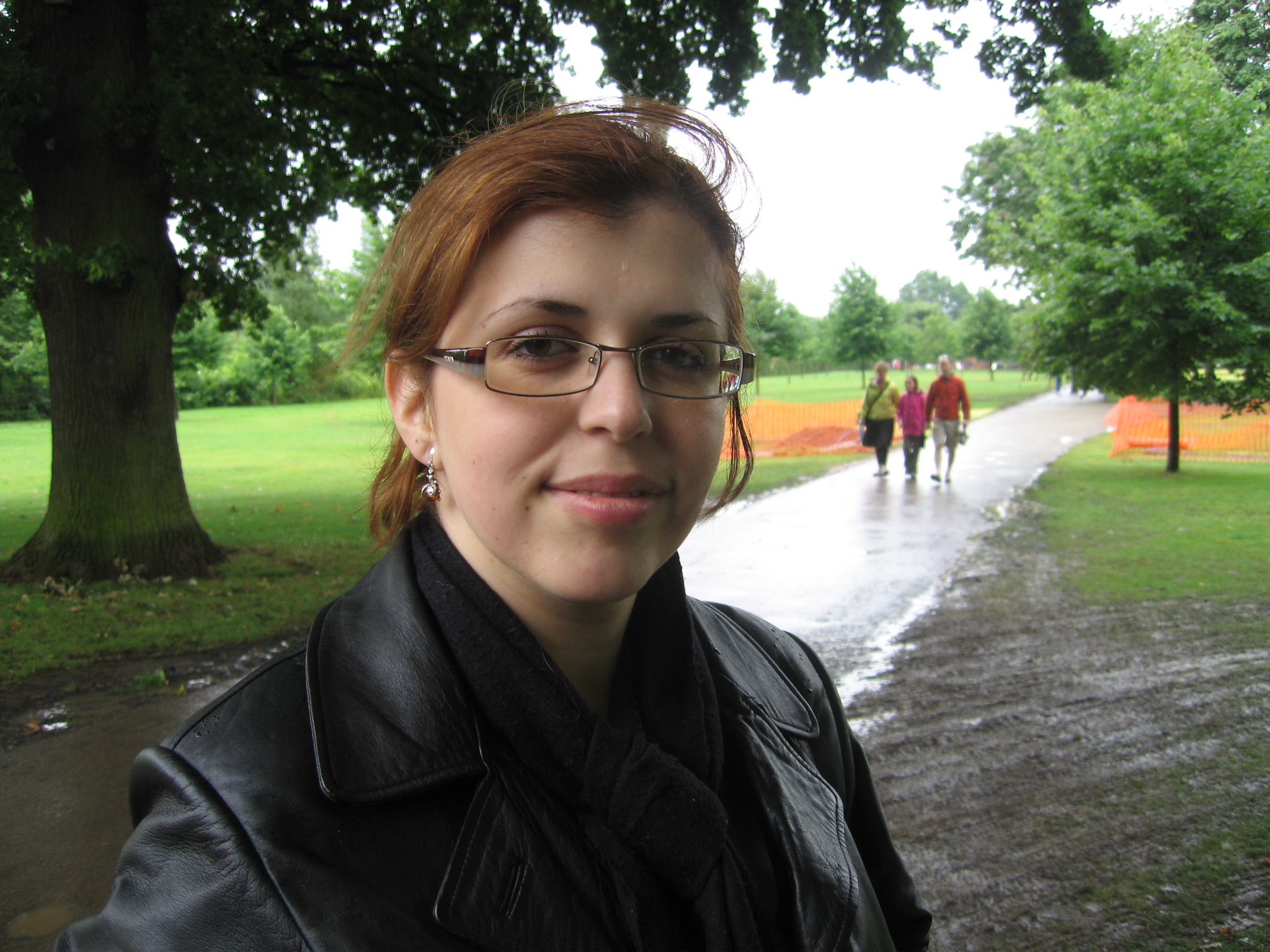 a woman wearing glasses in the rain, looking directly at the camera