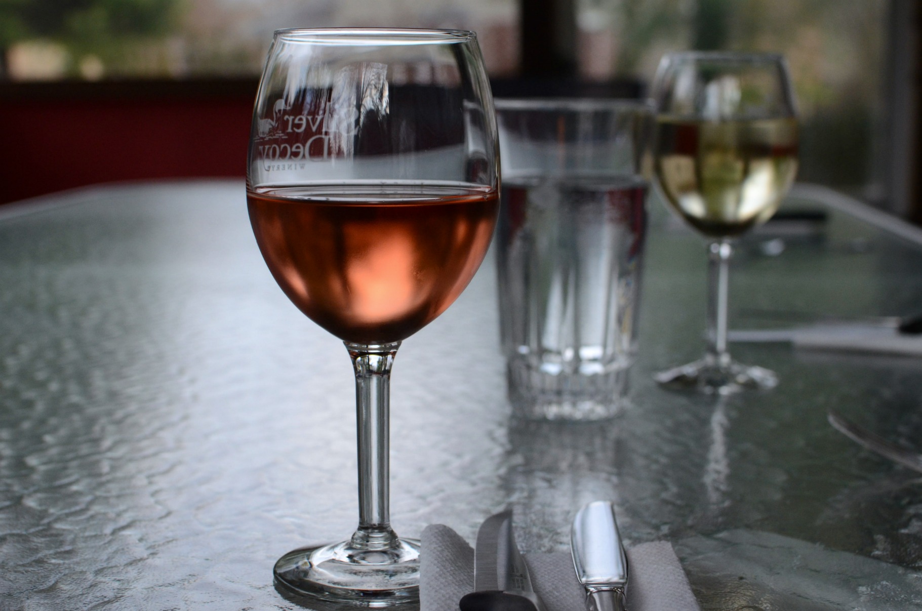 wine glass sitting on table with two glasses near one another