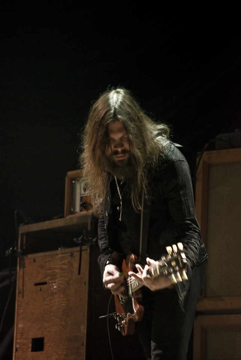 a man with long hair plays an electric guitar