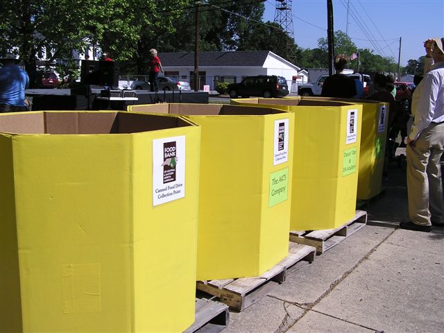 people walking on a sidewalk next to rows of yellow bins