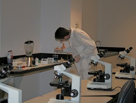 a man stands at a table with microscopes