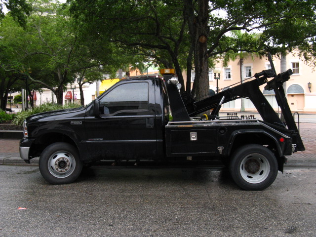 a black truck with a door lifted up is parked at the curb