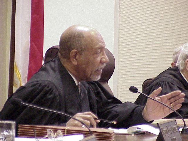 two men sit behind the judge as they speak