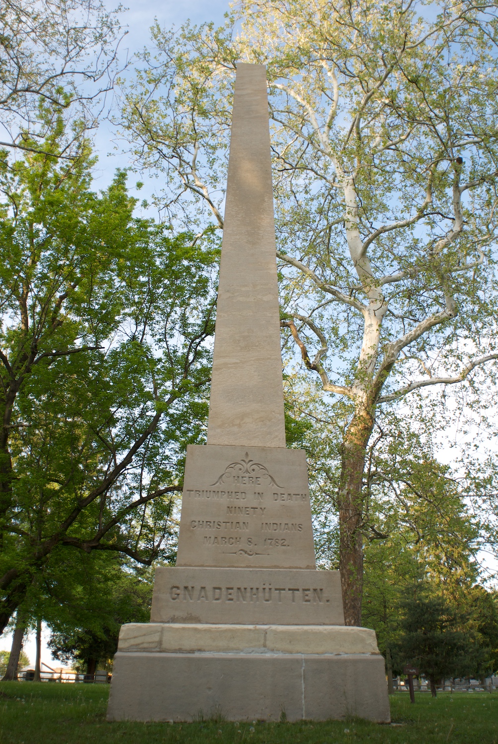 a obelisk that sits beneath a group of trees