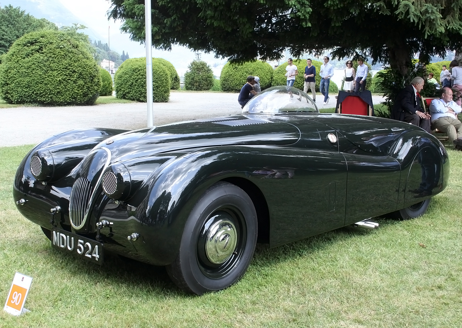 an old fashioned black sports car sits at a festival