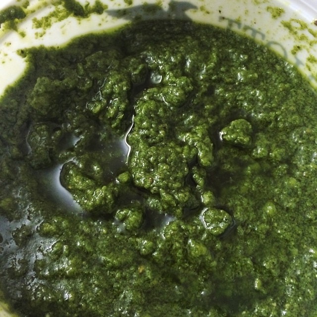 a bowl of green pesto is shown in close up view