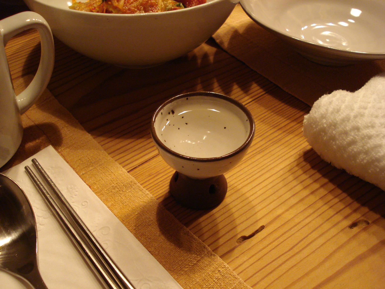 there are two bowls and spoons on a wooden table