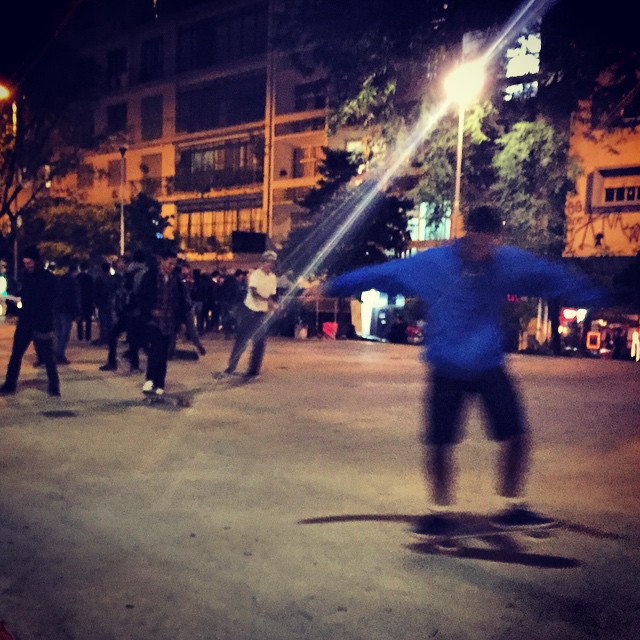 several people skateboarding down an empty street at night