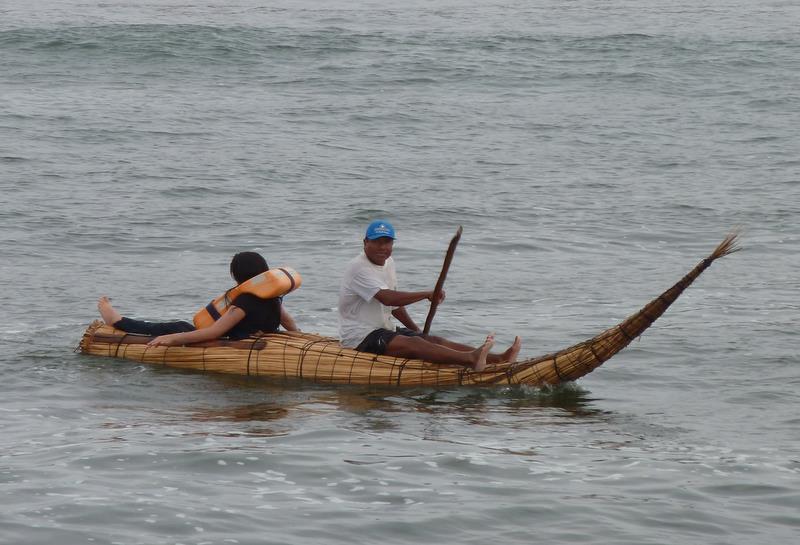 two people rowing a long bamboo boat across water