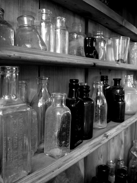 a large assortment of glass bottles are displayed on a shelf