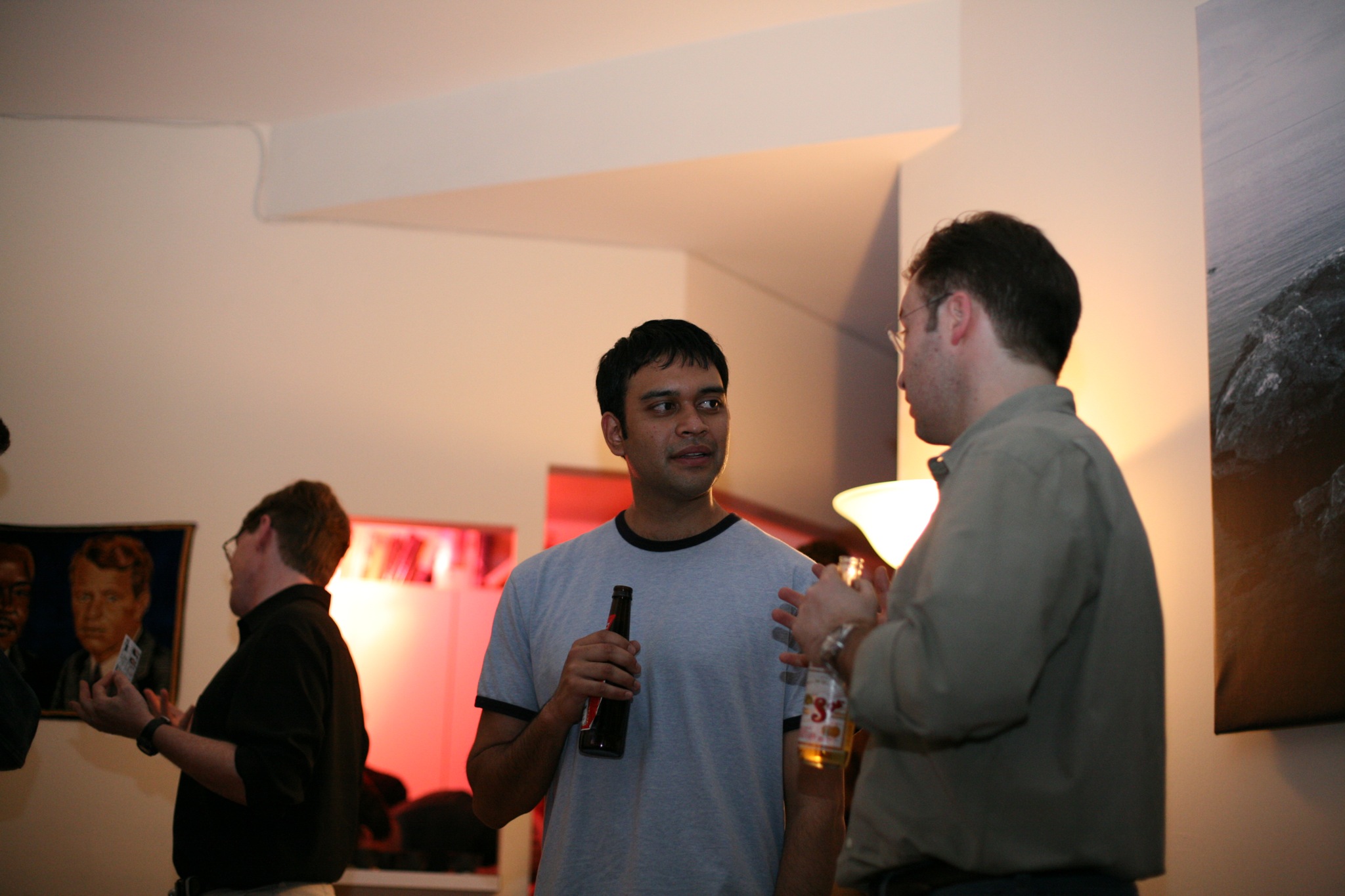 three men are standing in a room with some beers