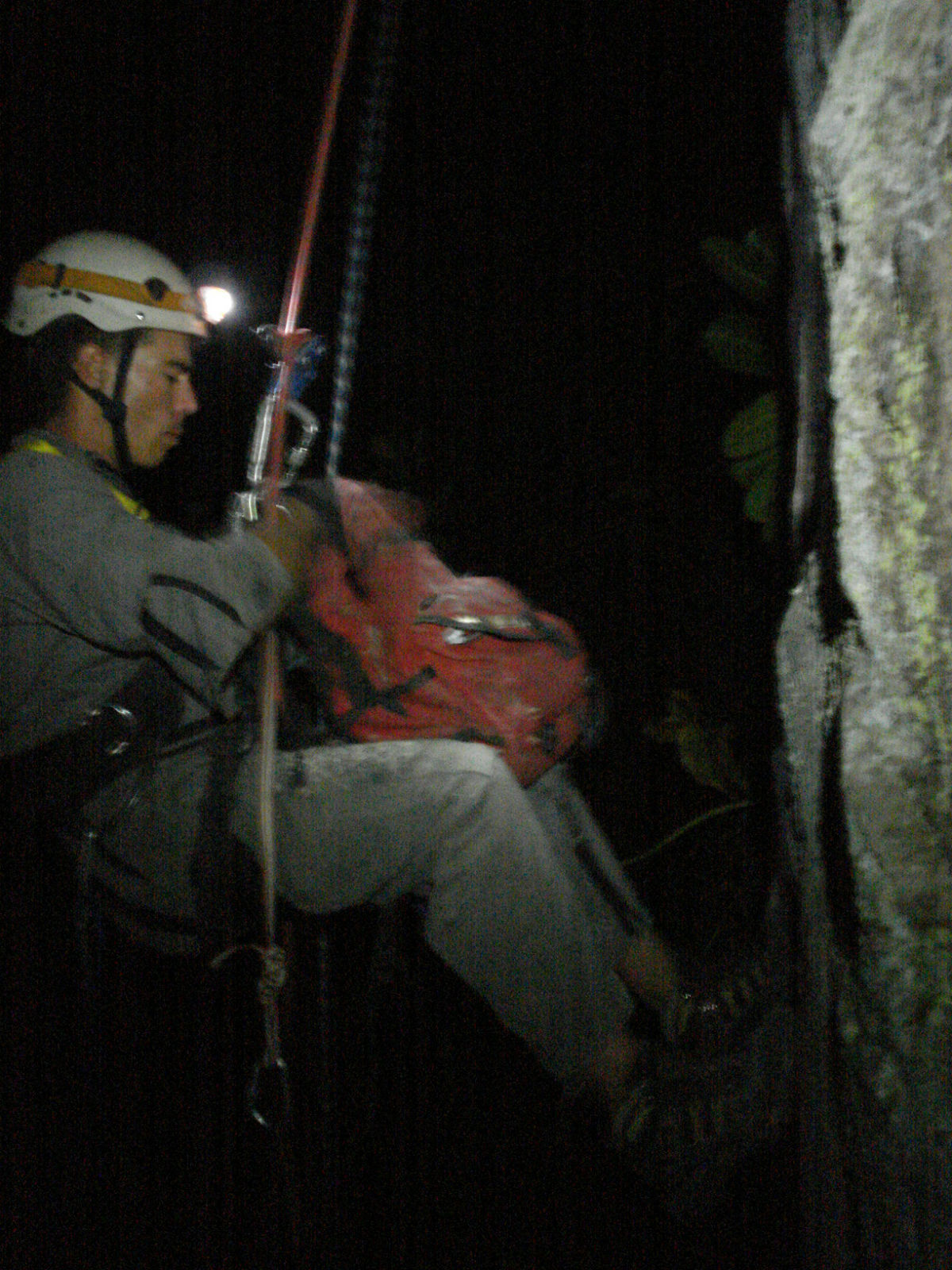 a man is climbing up a rope in the night