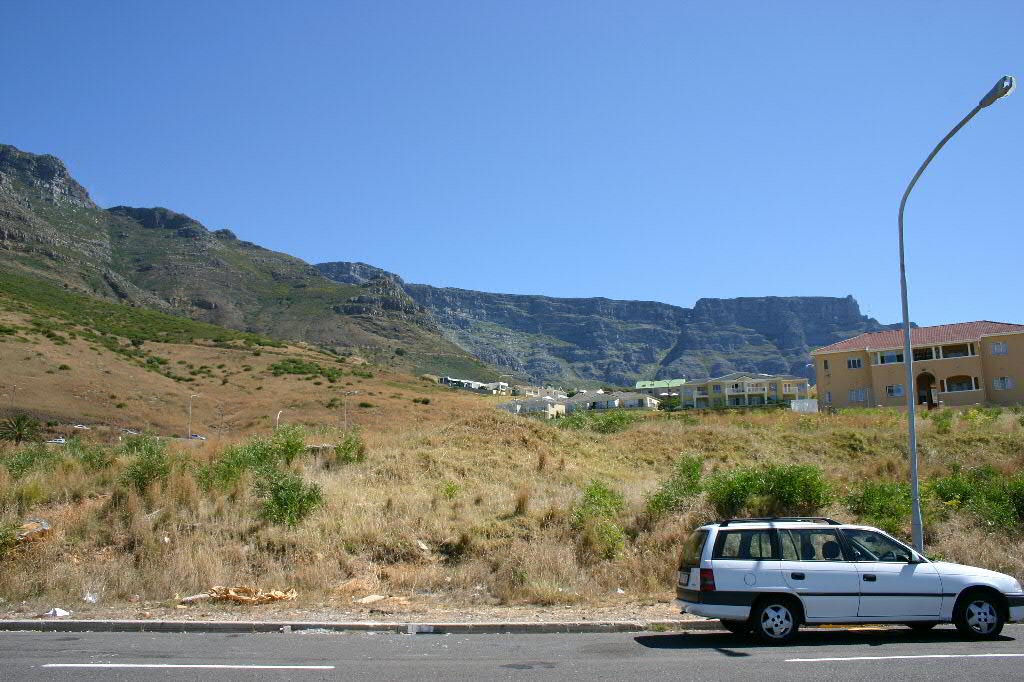 a small car is parked along the side of the road near mountains