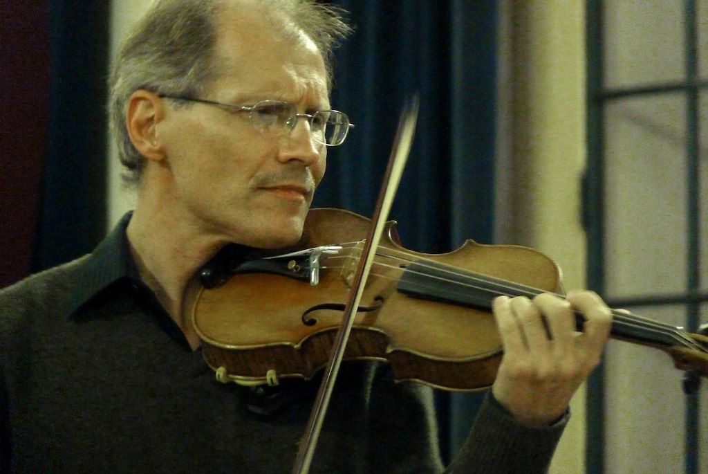 an old man with glasses playing the violin