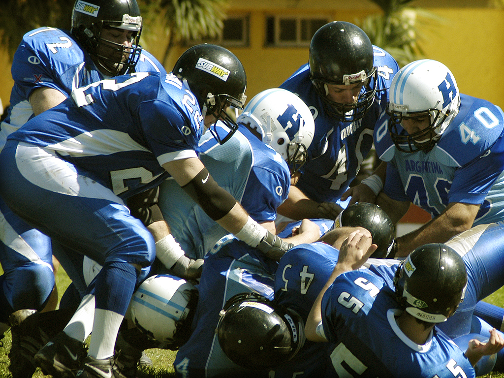 some football players standing and kneeling and holding onto each other
