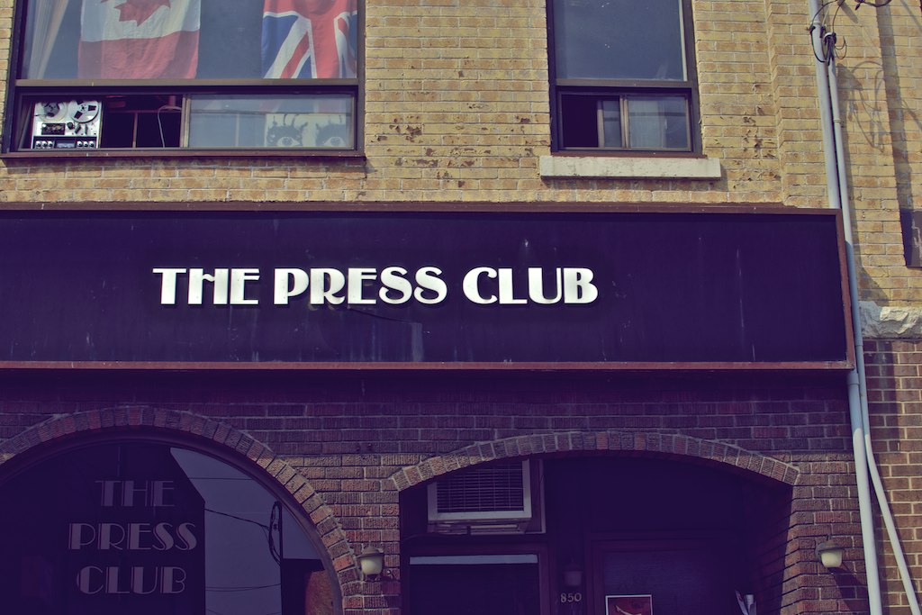 a tall brick building with a sign for the press club