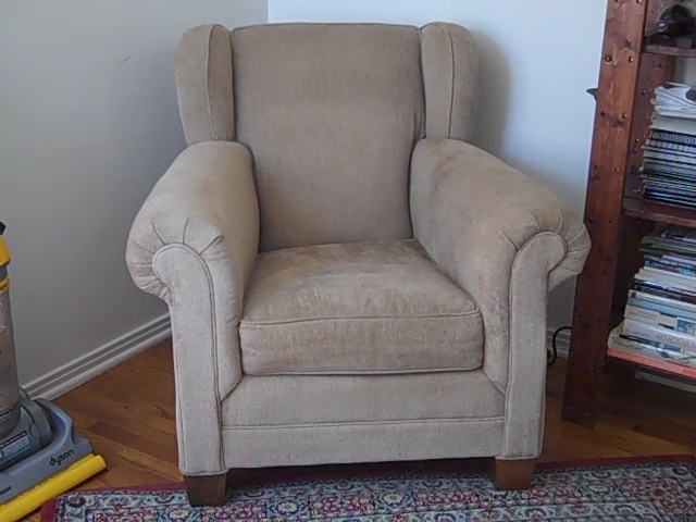a chair sitting in the corner with a carpet cleaner nearby