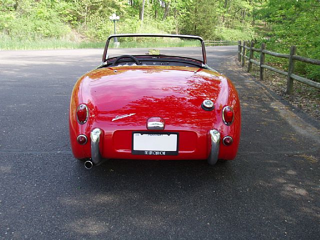an old red convertible convertible sits in a parking lot
