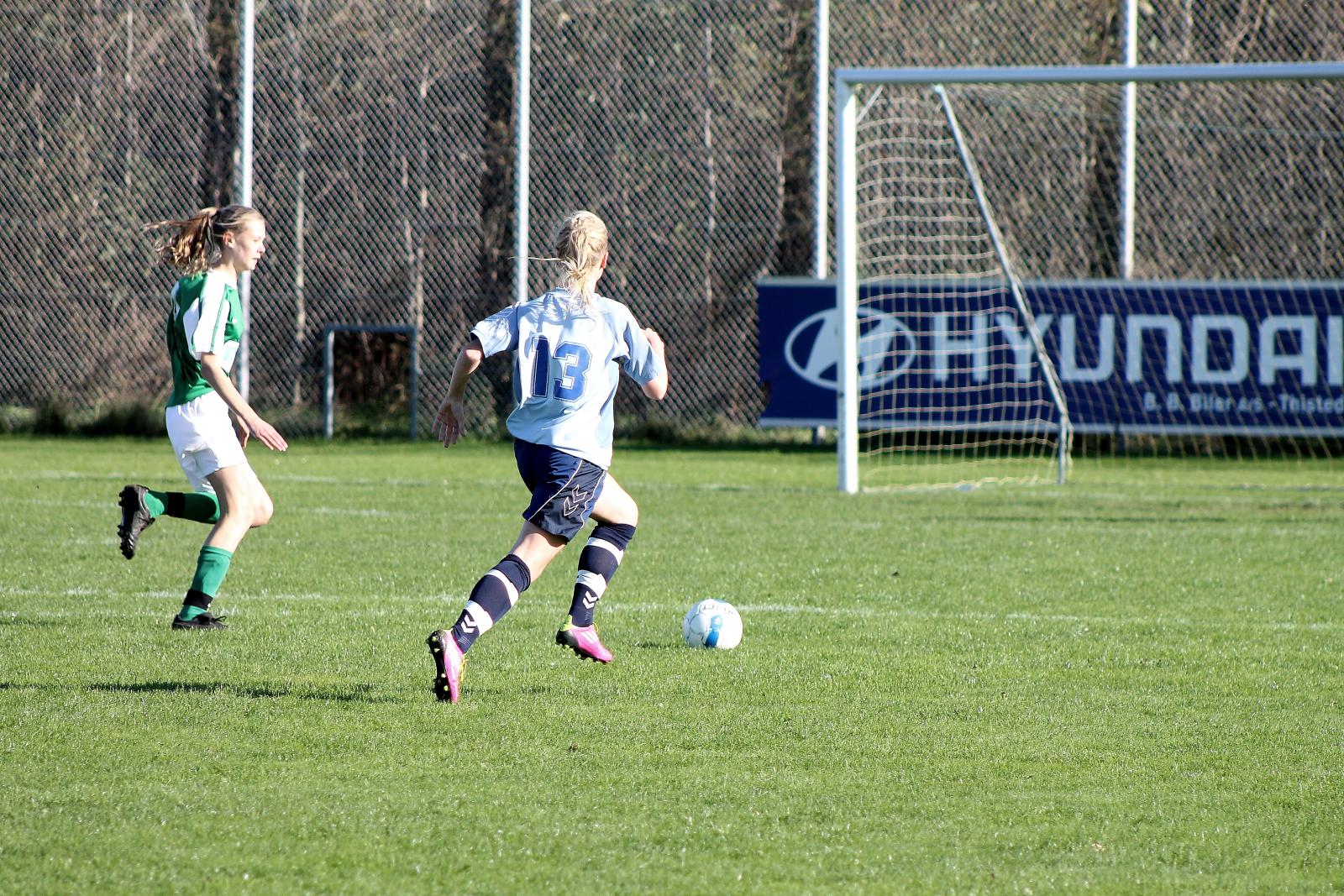 two soccer players on a grassy field are chasing the ball
