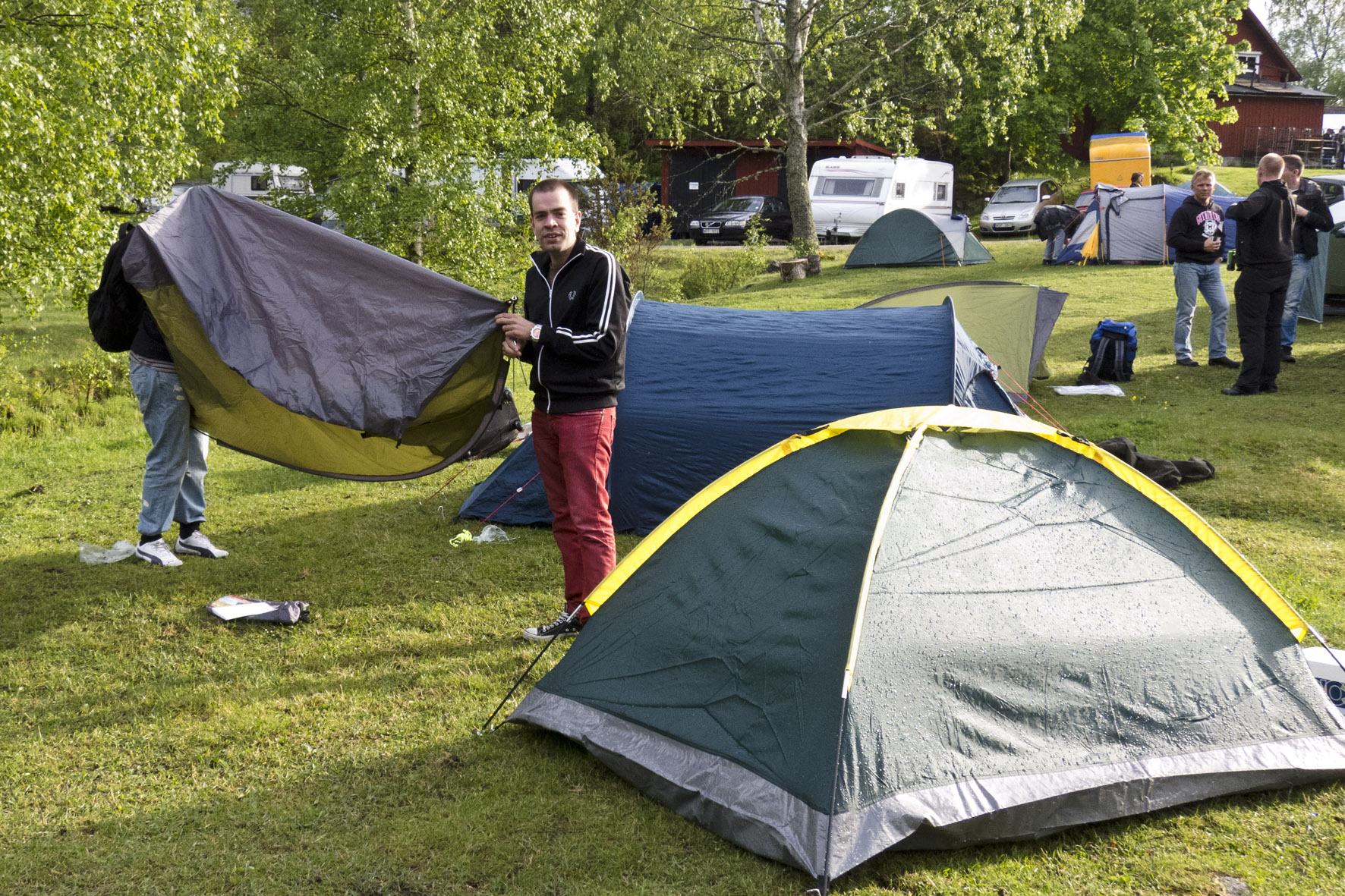 two men are standing next to tents with a tarp