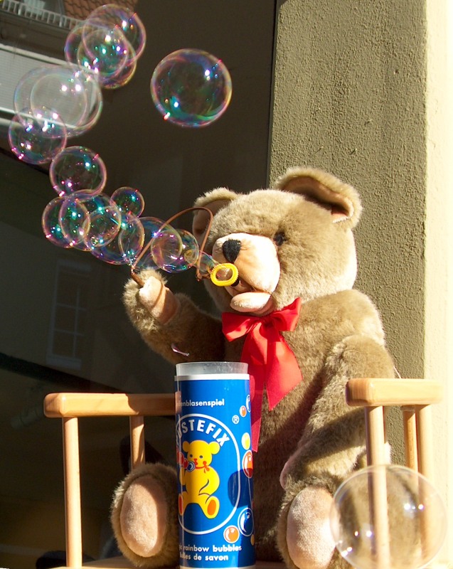 a brown teddy bear standing on top of a window sill