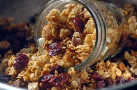 granola with raisins and nuts is falling in a bowl