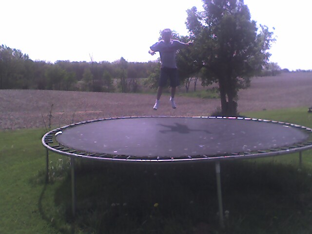 a man jumps high in the air on an above ground trampoline