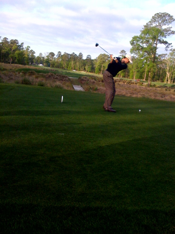 a man swinging his golf club at a ball in the grass