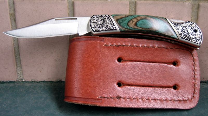a razor with silver decoration, resting on an old brown leather case